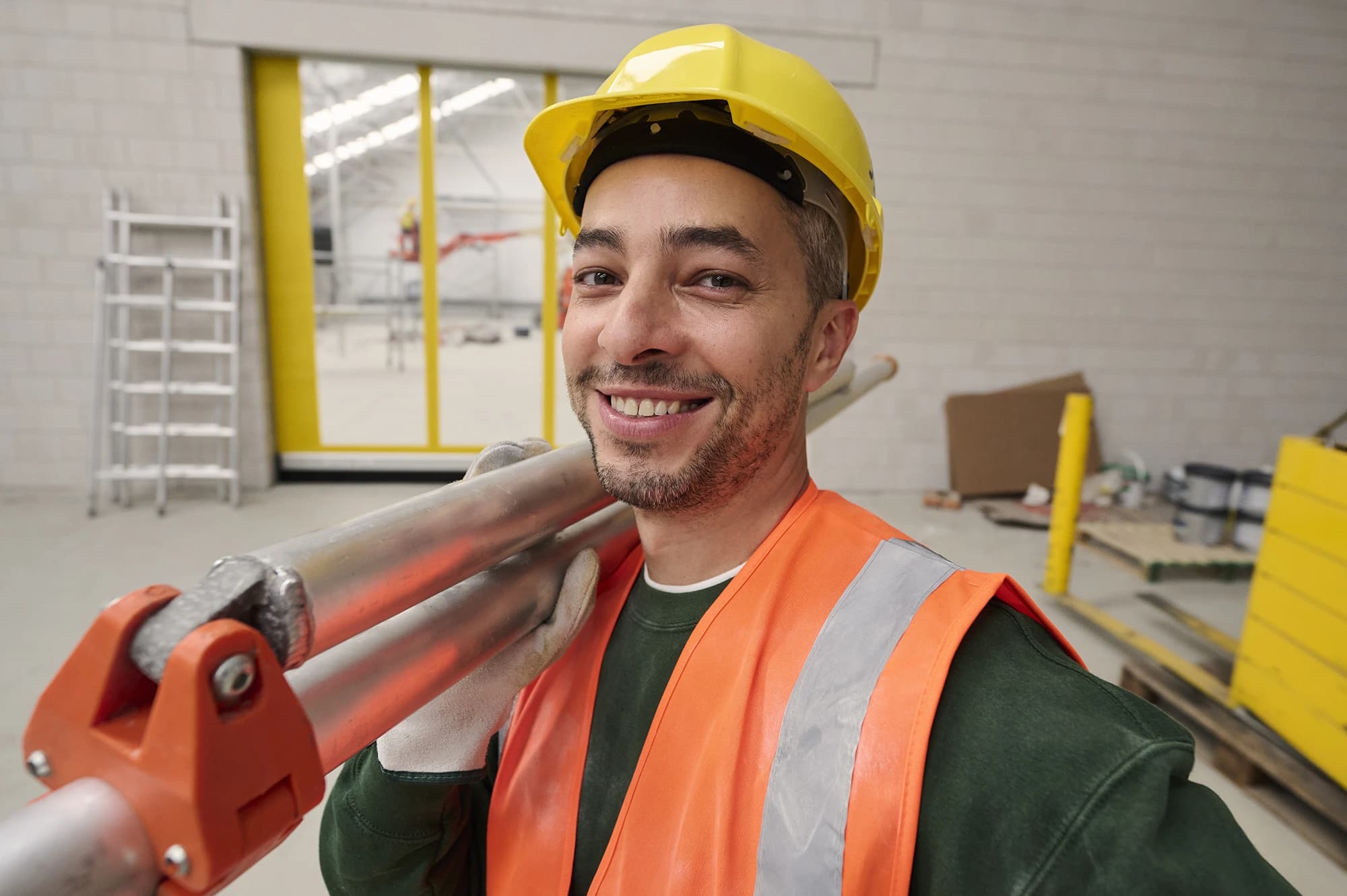 Pracownik budowlany w kasku i kamizelce odblaskowej uśmiecha się na budowie — oferty pracy w budownictwie z Accent